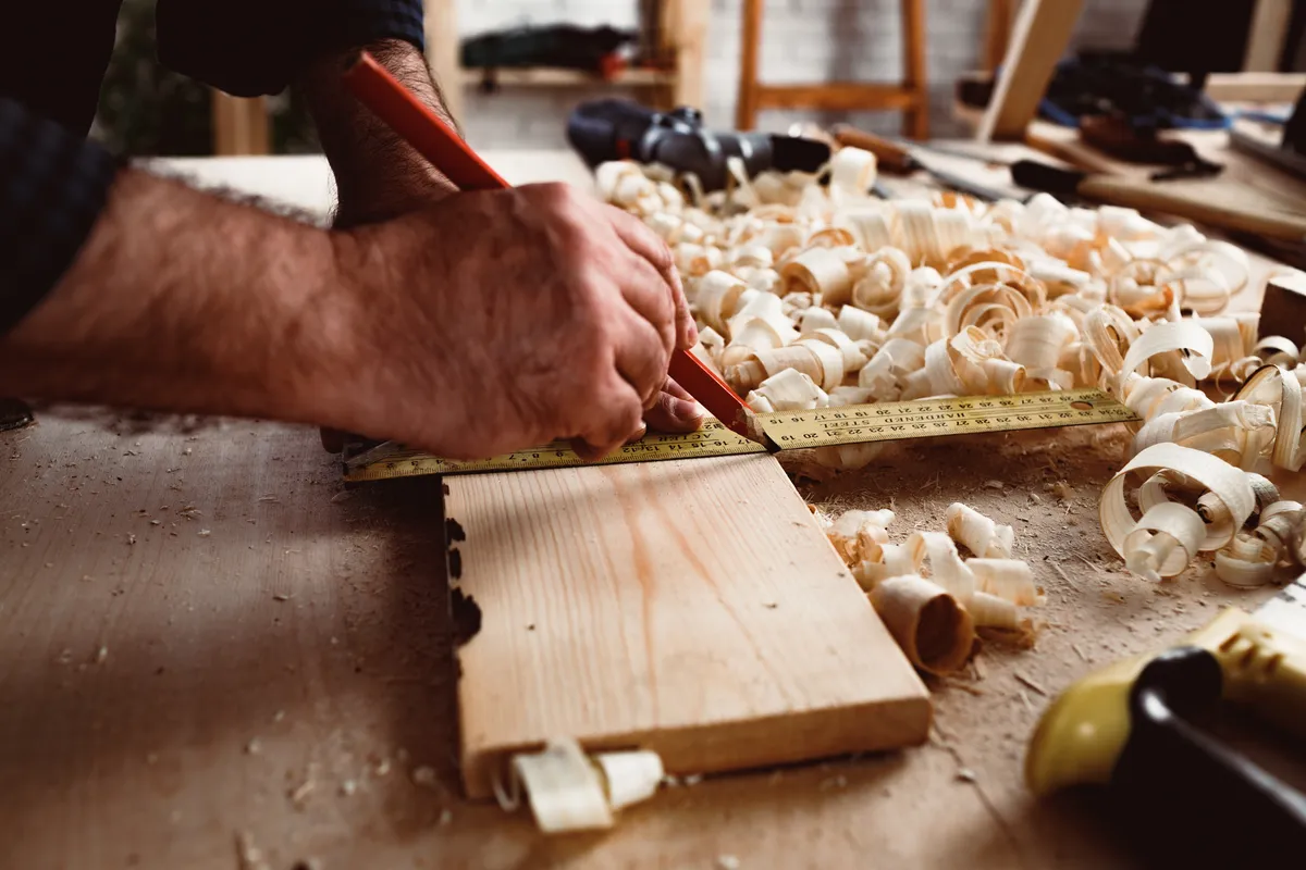 Carpenter makes pencil marks on a wood